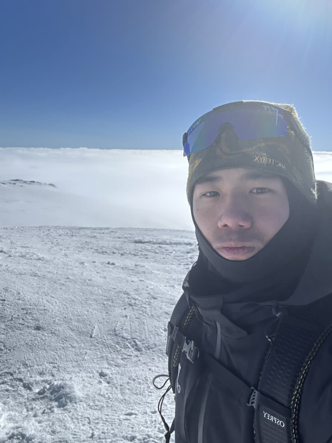 On a summit in full winter kit, with a flat sea of cloud below the ridgeline.